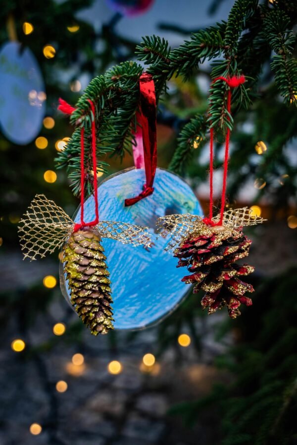 Close-up of decorative pine cones and blue circle ornament on Christmas tree with lights.