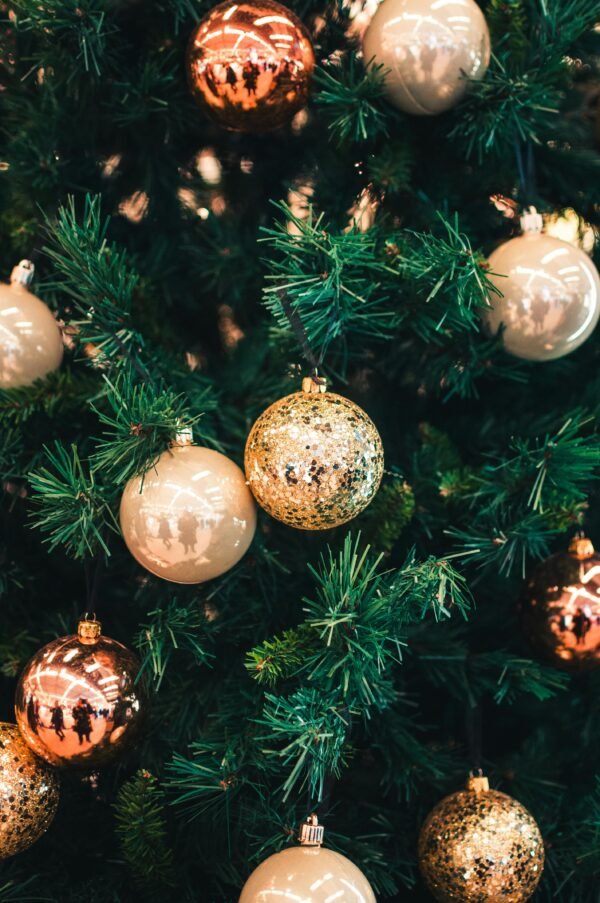 Festive holiday ornaments including gold and copper colors adorning a Christmas tree.